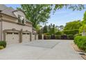 Three-car garage with a wide driveway and lush landscaping around the home's exterior at 8345 Jett Ferry Rd, Sandy Springs, GA 30350