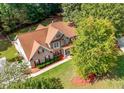 Aerial view of a two-story home with a brick exterior and a lush green lawn with mature trees at 140 Lost Forest Dr, Mcdonough, GA 30252