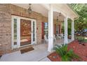 Inviting covered porch with white columns, seating area, and landscaped surroundings at 140 Lost Forest Dr, Mcdonough, GA 30252