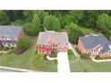 Aerial view of a large brick home with a two-car garage, surrounded by lush greenery and neighboring houses at 3500 Millwater Xing, Dacula, GA 30019