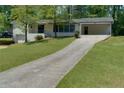 Exterior of a white home showcasing the long driveway leading up to a carport, surrounded by a green lawn at 1987 Darrell Dr, Marietta, GA 30066