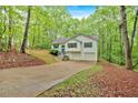 View of the home's exterior, featuring a large driveway and lush trees at 2539 Lakeside Dr, Villa Rica, GA 30180