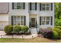 Beautiful home with white painted brick, dark shutters, manicured landscaping, and charming front entrance at 6000 Hampton Bluff Way, Roswell, GA 30075