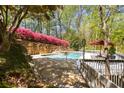 Backyard pool and deck area offering a private oasis with beautiful landscaping and a stone retaining wall with flowering shrubs at 6525 Old Riverside Nw Dr, Sandy Springs, GA 30328