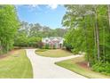Beautiful home with a circular driveway and lush trees surrounding the well-manicured lawn at 9465 Grande Dr, Winston, GA 30187