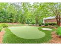 Private putting green featuring manicured synthetic grass, a sand trap, and mature landscaping at 9465 Grande Dr, Winston, GA 30187