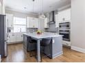 Modern kitchen with stainless steel appliances, gray island, pendant lights, and decorative tile backsplash at 834 S Columbia Dr, Decatur, GA 30030