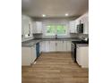 Bright kitchen features white cabinets, granite countertops, new appliances, and modern wood grain flooring at 3080 Hogan Sw Rd, Atlanta, GA 30331
