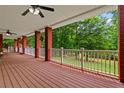 Long covered porch with wooden deck and white railings offering a serene view of the lush greenery at 7180 Westray Rd, Cumming, GA 30028