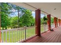 Expansive covered porch with brick pillars, wooden deck, and white railing showcasing the lush greenery at 7180 Westray Rd, Cumming, GA 30028