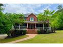 Elegant brick home featuring a covered front porch and beautifully manicured lawn at 2230 Cammie Wages Rd, Dacula, GA 30019