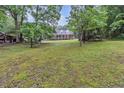 Exterior view of charming home featuring a sprawling front porch surrounded by mature trees at 143 Navajo Trl, Rydal, GA 30171
