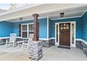 Inviting front porch featuring rocking chairs, stone pillars, and a dark wooden door with decorative sidelights at 505 Alta Ct, Villa Rica, GA 30180