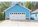 Two-car garage featuring a white door with black hardware and stone accents on a charming blue home at 505 Alta Ct, Villa Rica, GA 30180