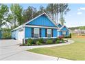 Side view of the blue house showcasing a two-car garage with a well-maintained lawn and tasteful landscaping at 505 Alta Ct, Villa Rica, GA 30180