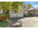 Wide, patterned brick driveway leading to a home with a two-car garage surrounded by vibrant greenery at 2651 Briarlake Rd, Atlanta, GA 30345
