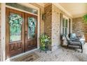 Inviting front porch with double wood doors, brick accents, outdoor seating and plants at 106 Stephens Farm Dr, Canton, GA 30115