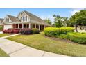 Exterior view showcasing lush lawn, attractive shrubbery, brick facade, and a covered porch lined with columns at 2055 Hickory Station Cir, Snellville, GA 30078