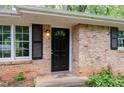 Close-up of a brick house entrance with a black door, black shutters, and natural light at 980 Oakton Sw Dr, Marietta, GA 30060