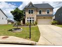 Inviting brick home showcasing a two-car garage and a landscaped yard with a tree at 4935 Bellehurst Ln, Cumming, GA 30040