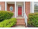Close up of the brick front porch featuring a red front door, white pillars, and neat landscaping at 3270 Golfe Links Dr, Snellville, GA 30039