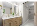 Modern bathroom featuring double sinks, wood cabinets, gold fixtures, and a walk-in closet with sliding barn door at 1911 Rollingwood Se Dr, Atlanta, GA 30316