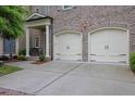 Lovely brick home with a two-car garage, featuring arched doorways and concrete driveway and walkway at 125 Windy Pines Pass, Roswell, GA 30075