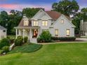Charming two-story brick home with a landscaped front yard and a welcoming front porch at dusk at 4235 Night Sky Ln, Cumming, GA 30041