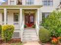Inviting front entrance featuring a vibrant red double door, a covered porch, and manicured landscaping at 4235 Night Sky Ln, Cumming, GA 30041