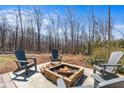 Outdoor brick firepit with chairs is surrounded by beautiful trees, creating a cozy and inviting space for relaxation and entertainment at 6265 Reives Rd, Cumming, GA 30041