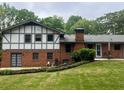 Brick two-story home with a chimney, French doors, landscaped yard, and outdoor seating area at 3996 Indian Manor Dr, Stone Mountain, GA 30083
