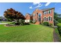 Well-maintained brick house on a sprawling green lawn featuring mature trees and professionally designed landscaping at 2436 Camden Lake Nw Vw, Acworth, GA 30101