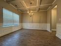 Dining room featuring hardwood floors, coffered ceilings, wainscotting, a window, and modern chandelier at 3592 Hancock Vw, Decatur, GA 30034