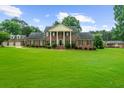 Brick home with a large front lawn, stately columns, a circular driveway and mature landscaping at 130 Plantation Dr, Stockbridge, GA 30281