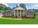 Brick home with stately white columns, black shutters, landscaped yard, and a well-maintained lawn at 130 Plantation Dr, Stockbridge, GA 30281