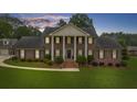Frontal view of a brick home with white columns, black shutters, and manicured shrubbery at 130 Plantation Dr, Stockbridge, GA 30281