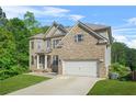 Two-story brick home with a well-kept lawn and a spacious driveway leading to a garage at 15 Manas Ct, Covington, GA 30016