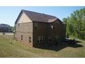 Back exterior view of brick house with lawn, patio set on concrete, and trees at 504 Liverpool Dr, Mcdonough, GA 30252
