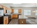 Well-lit kitchen with wood cabinets, black appliances, center island and modern wood-look flooring at 229 Millwheel Dr, Villa Rica, GA 30180