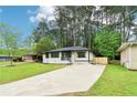 Landscaped front yard leading to a charming home with a concrete driveway and wooden accent shutters at 117 Hillsdale Dr, Atlanta, GA 30315