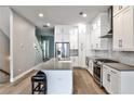 Open-concept kitchen boasts white cabinets, stainless steel appliances, and an island with seating, with hardwood floors at 247 Franklin Rd, Atlanta, GA 30342