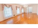 Bright living room featuring gleaming hardwood floors, chandelier, and large windows at 3560 Emily Way, Atlanta, GA 30349