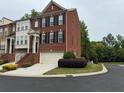 Brick townhome featuring an attached garage, small shrubbery, and a view of the tree-lined street at 4888 Colchester Se Ct # 3, Atlanta, GA 30080