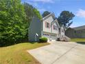 Exterior view of a well-maintained home with a two-car garage and a spacious driveway, set against a backdrop of trees at 156 Hawthorn Dr, Carrollton, GA 30116