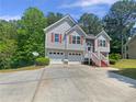 Charming exterior showcasing a two-car garage, red shutters, well-maintained landscaping, and beautiful natural surroundings at 156 Hawthorn Dr, Carrollton, GA 30116