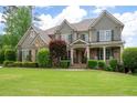 Charming two-story home featuring a well-manicured lawn, stone accents, and a welcoming front porch with rocking chairs at 3309 Nw Past Nw Pl, Kennesaw, GA 30152