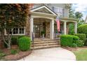 Inviting front porch with stone columns, flag, and manicured bushes leading to the front door at 3309 Nw Past Nw Pl, Kennesaw, GA 30152
