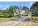 Inviting two-story home with yellow siding, stone accents, front porch and attached garage at 2100 Ann Se Ct, Conyers, GA 30013
