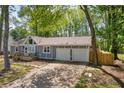 View of a well-maintained home with a two-car garage, driveway, and mature trees at 1660 Rose Garden Ln, Loganville, GA 30052