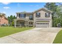 Attractive two-story brick home with a covered porch, two-car garage, and a well-manicured lawn under a bright sky at 2055 Deans Landing Dr, Lawrenceville, GA 30043